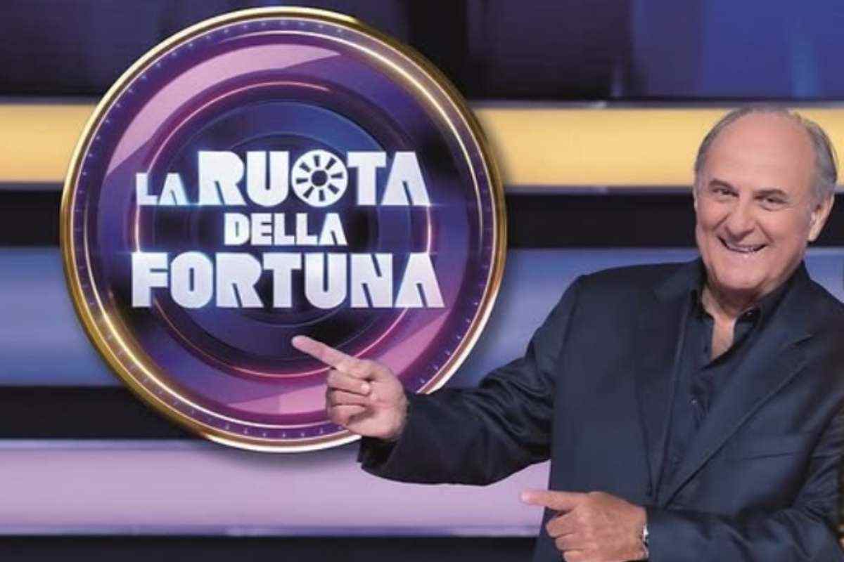 Gerry Scotti indica il logo della Ruota della Fortuna